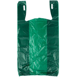 Os sacos de compras na mercearia da cor verde, t-shirt plástico ensacam a favor do meio ambiente